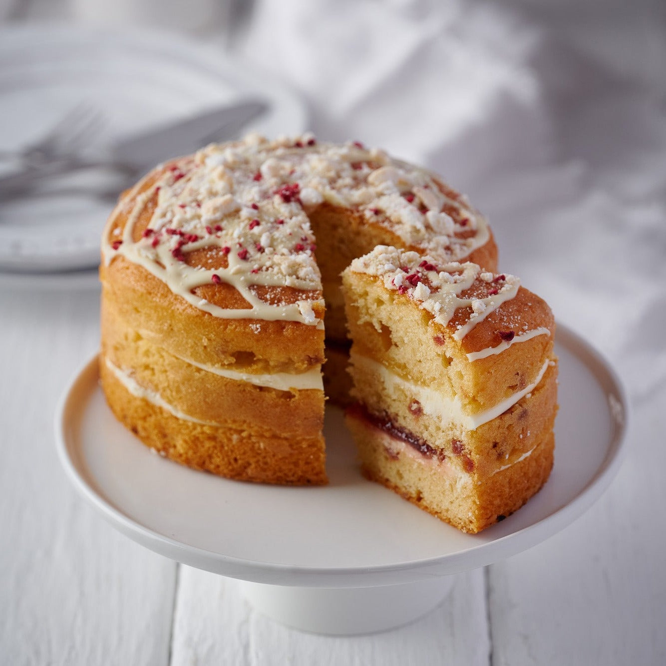 a 6 inch lemon and raspberry meringue cake with a slice cut out