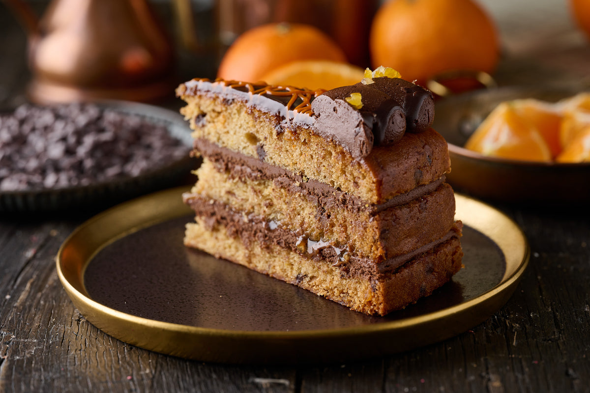 slice of sticky jaffa cake with ornage sponge, chocolate frosting, orange maramalade and finished with candied orange pieces.