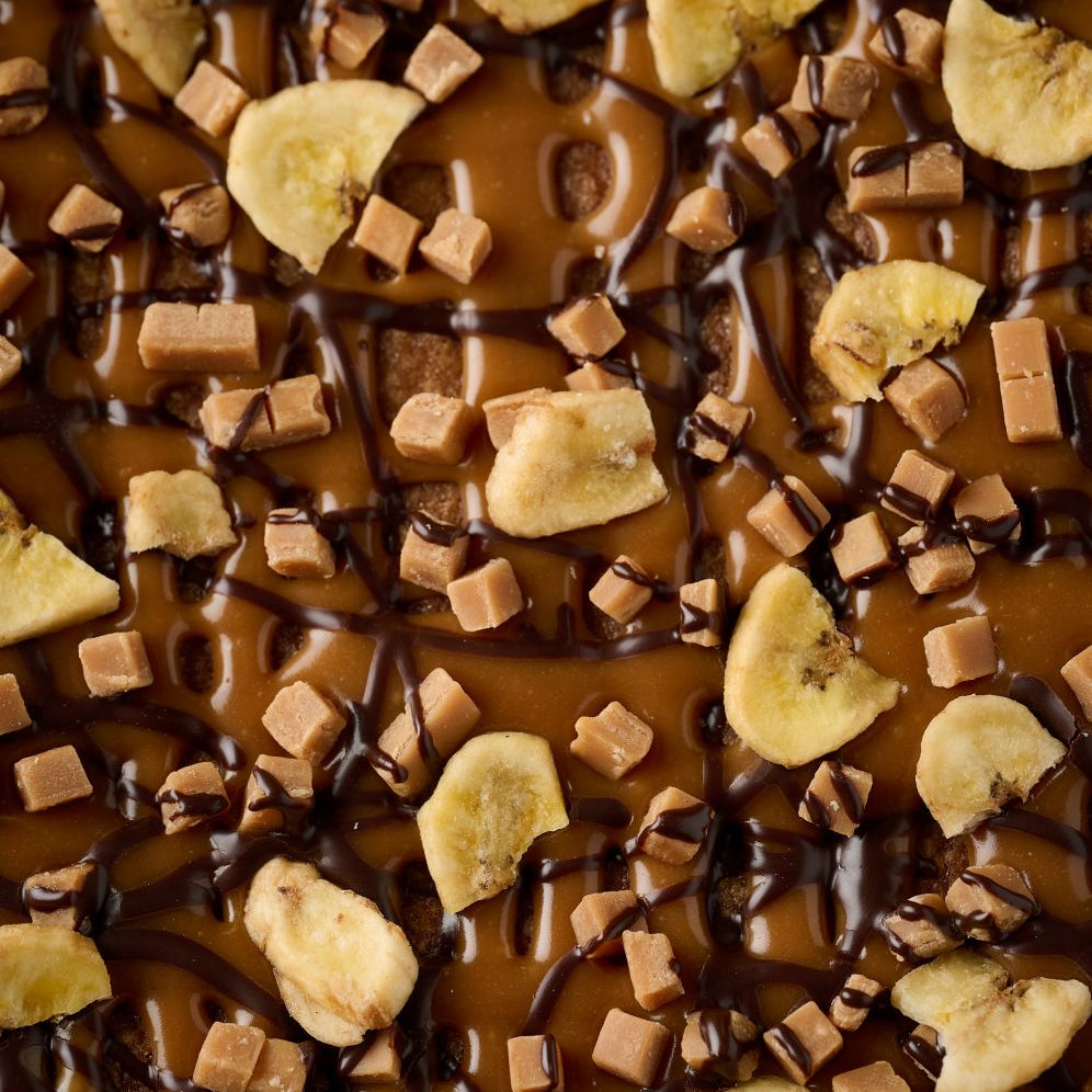close up of banoffe tart topped with caramel, fudge, banana chips and dark chocolate.