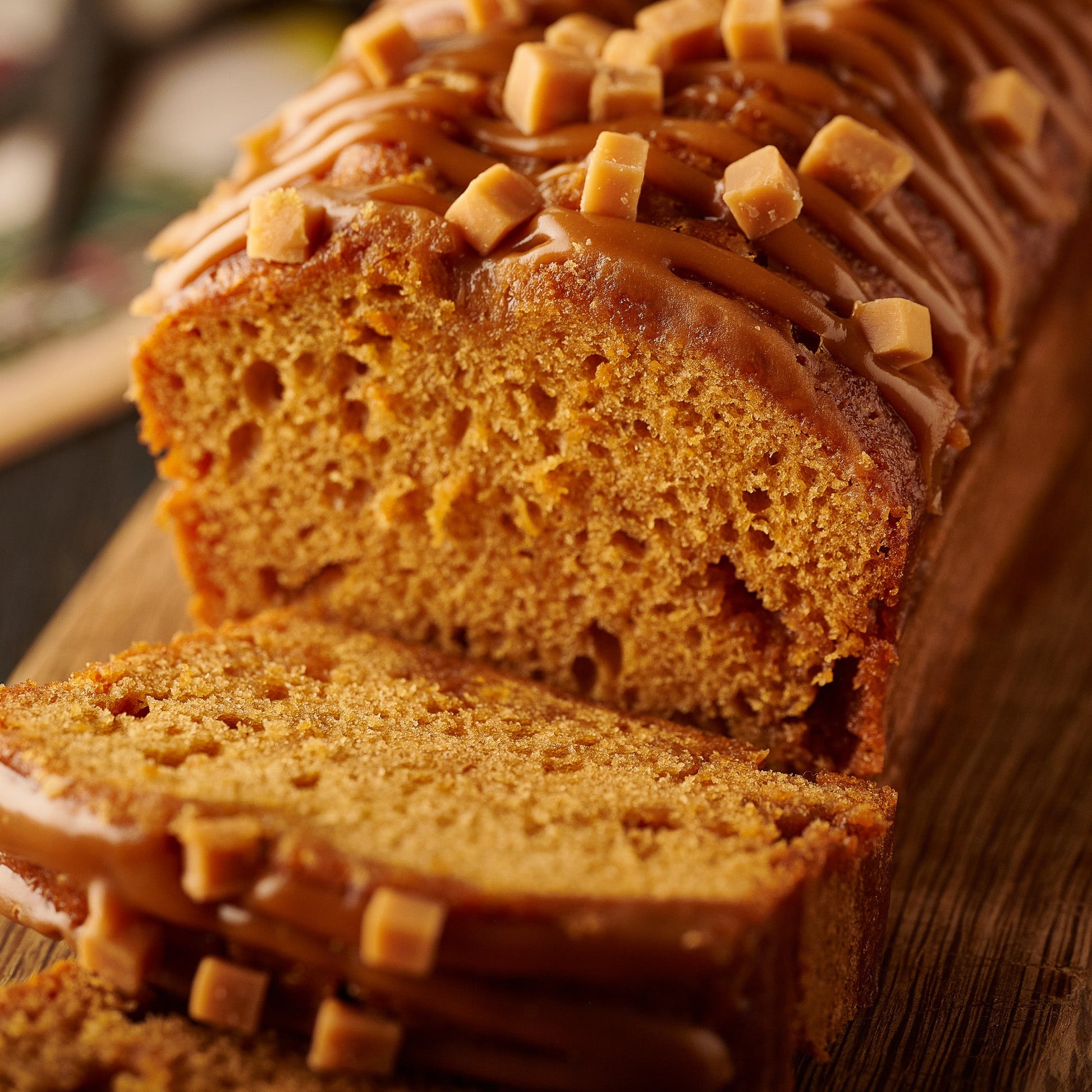 sticky toffee loaf cake sliced topped with caramel and fudge pieces 