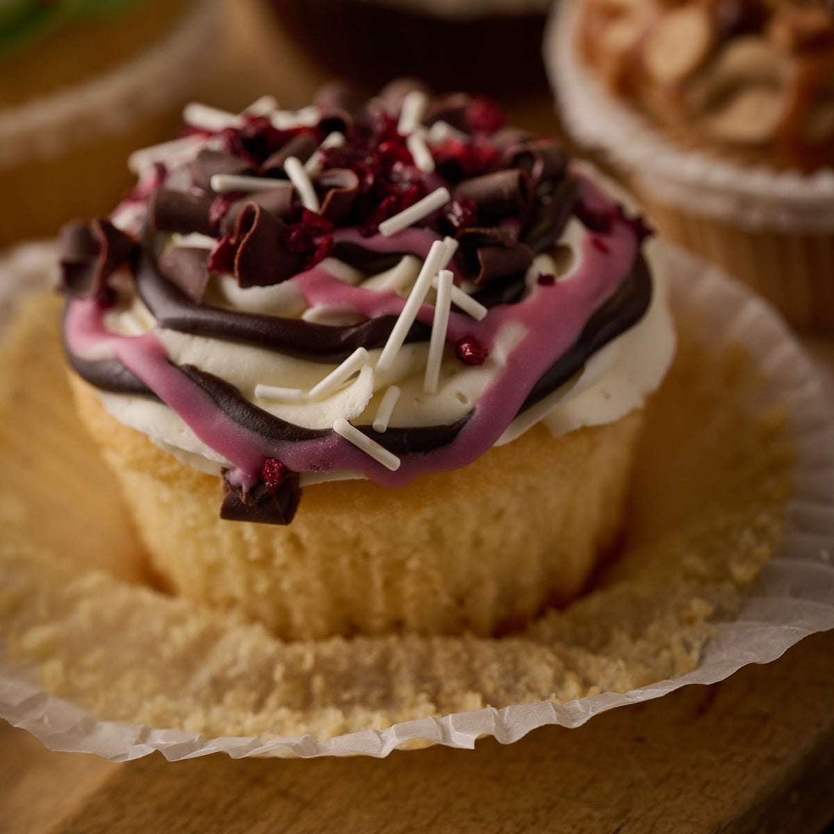 chocolate and cherry cupcake finished with drizzles of chocolate, dark chocolate curls and candies cherries 