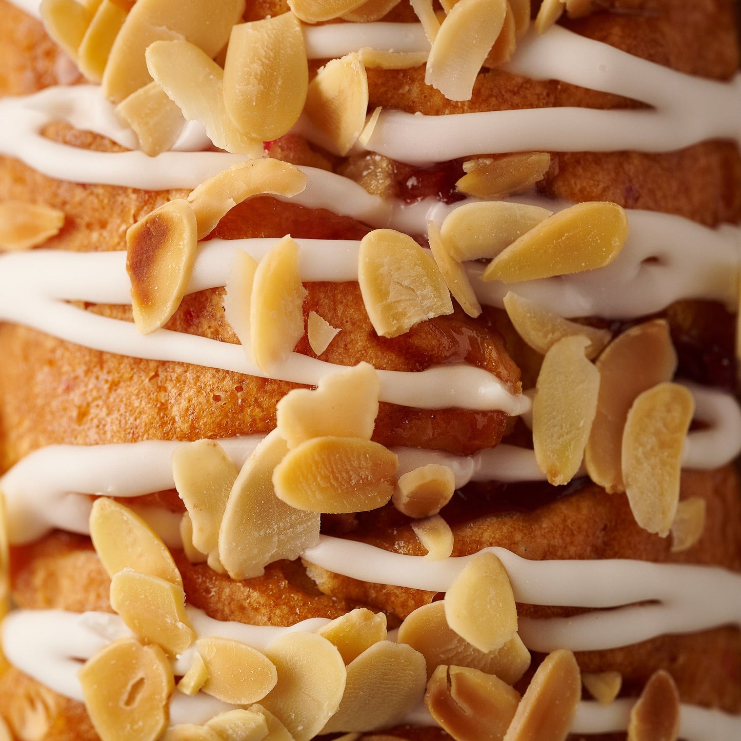 close up of cherry bakewell loaf cake with icing drizzle and toasted flaked almonds