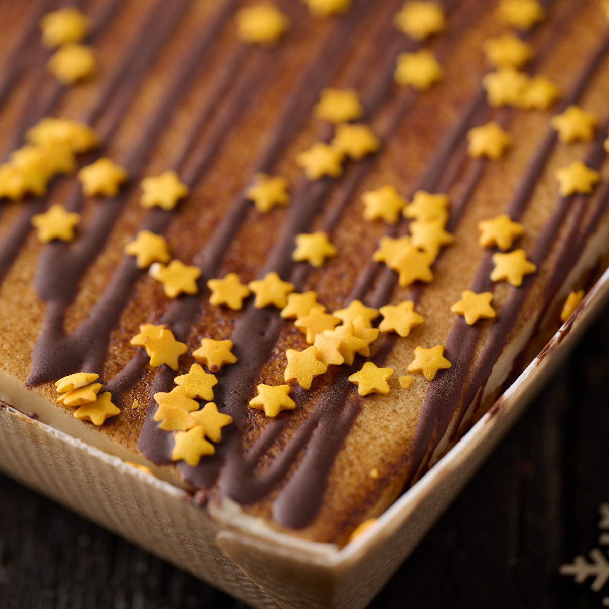 close up or christmas mincemeat and toasted marzipan tart finished with chocolate drizzle and gold sugar stars
