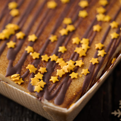 close up or christmas mincemeat and toasted marzipan tart finished with chocolate drizzle and gold sugar stars