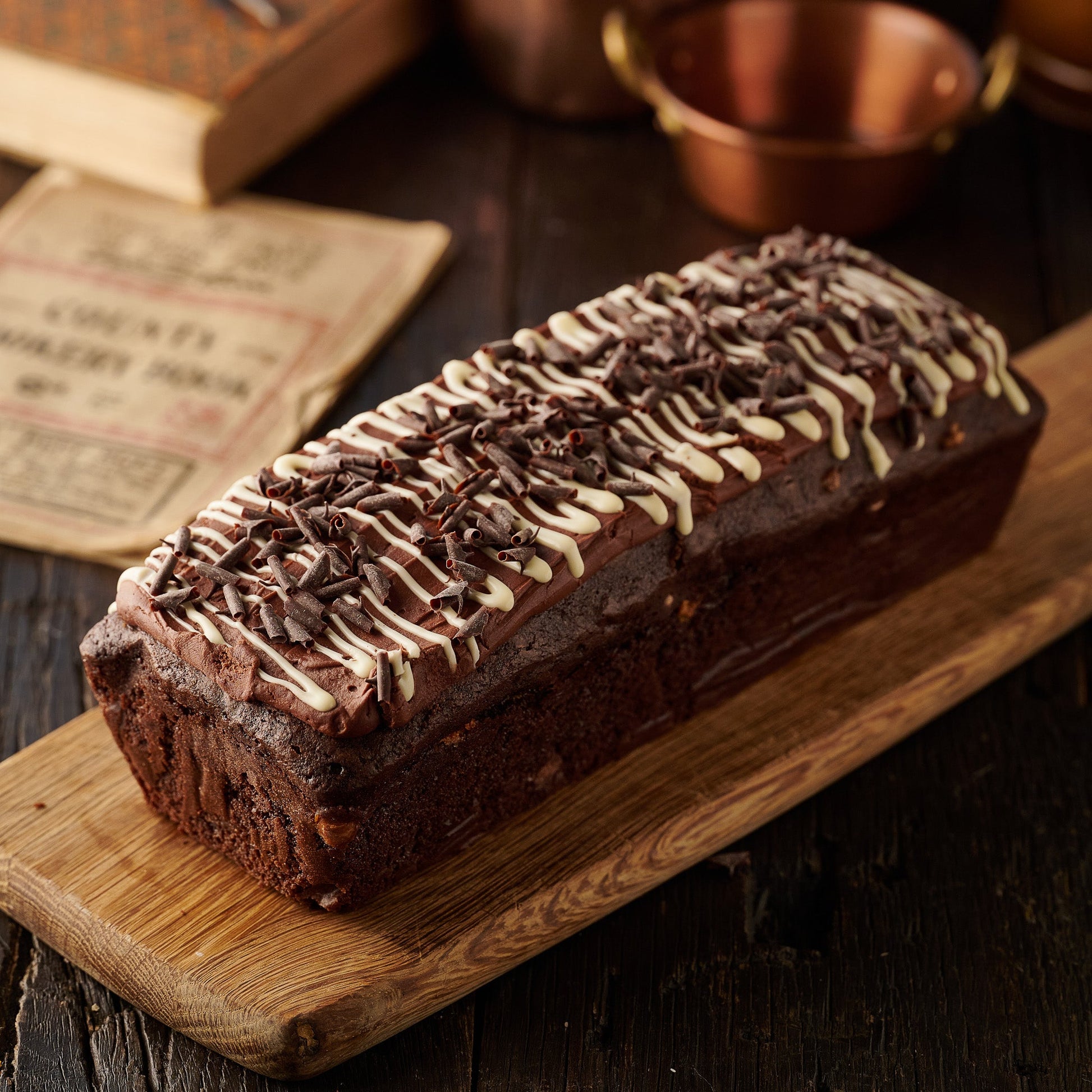 triple chocolate loaf cake with chocolate frosting white chocolate drizzle and dark chocolate curls
