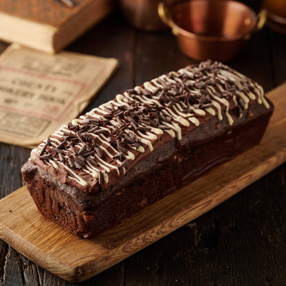 triple chocolate loaf cake with chocolate frosting white chocolate drizzle and dark chocolate curls