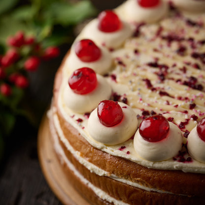 vegan cherry trifle cake topped with vanilla frosting and glace cherries 